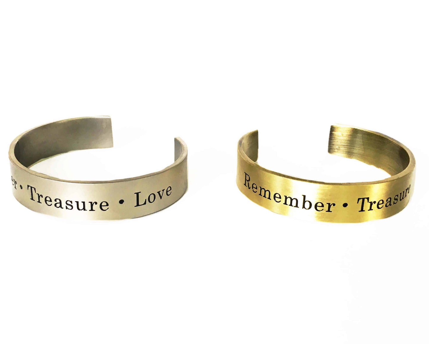 Two Simply Eartha cuff bracelets by Simply Eartha, one silver and one antique gold, engraved with words like "Treasure," "Love," and "Remember." Open-ended brass design shown on a white background.